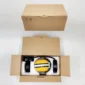 Brown cardboard box opened to reveal black and yellow noise-cancelling headphones inside, next to a closed identical box.