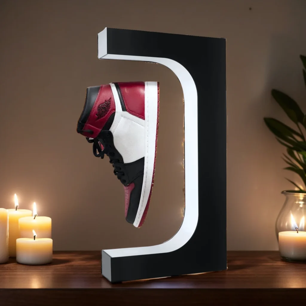 A sneaker in red, white, and black is showcased on a Floating Shoe Stand that is illuminated and set on a table adorned with lit candles.