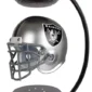 A floating silver and black Raiders football helmet suspended between two black magnetic bases.