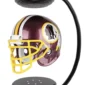 A maroon football helmet with yellow facemask floats within a black magnetic stand.