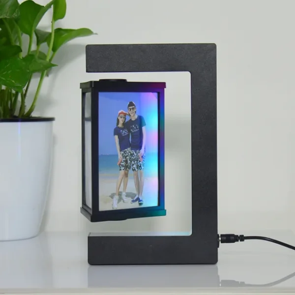 Magnetic Levitating Picture Photo Frame Creative Night Light With Led Lights Display Birthday Christmas Gift – black 10 A levitating photo frame with a couple's picture, featuring a modern black design. A potted plant sits beside it on a white surface.