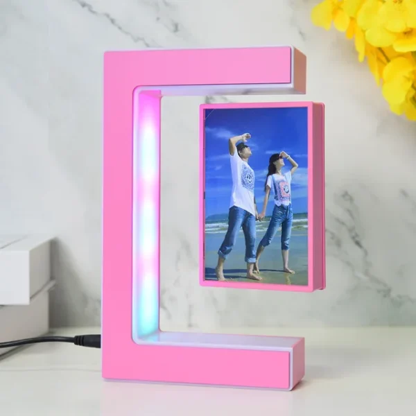 Magnetic Levitating Picture Photo Frame Creative Night Light With Led Lights Display Birthday Christmas Gift – pink 9 A pink C-shaped LED photo frame with a couple's picture inside. The frame is on a white surface, next to a stack of books and a yellow flower.
