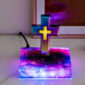 The Floating Cross Nightlight, with its multicolor lights and Greek cross design, sits elegantly on a galaxy-patterned base on a marble surface.