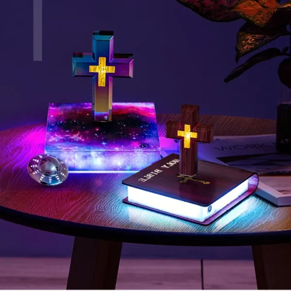 Christmas gift Personalized gifts home decoration Magnetic levitation cross floating crass table lamp RGB color 3 Colorful illuminated crosses on books with glowing bases are displayed on a wooden table alongside a decorative object.