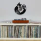 Wall-mounted cat-themed clock above a shelf full of vinyl records and a record player.