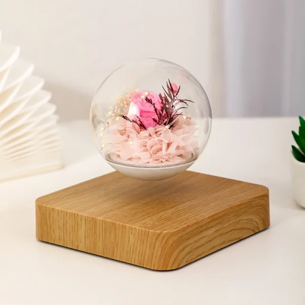 Magnetic Levitating Preserved Flower Rotation Flower Lamp Creative Floating LED Night Light For Home Desk Office Decoration 3 Levitating glass orb with pink flowers inside, supported by a wooden base, placed on a white surface.