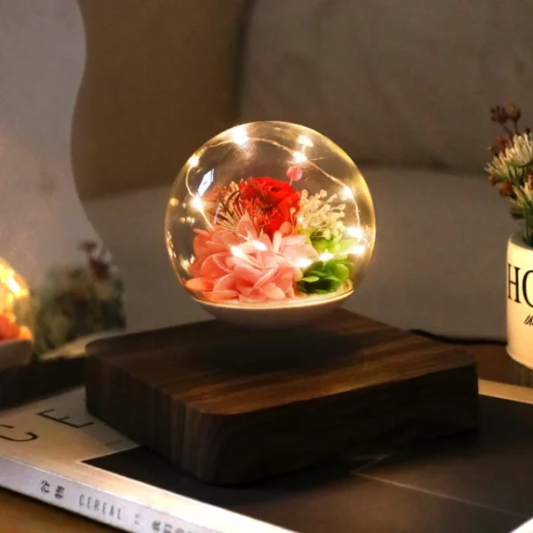 Magnetic Levitating Preserved Flower Rotation Flower Lamp Creative Floating LED Night Light For Home Desk Office Decoration – Dark Color 8 A levitating glass globe contains illuminated flowers and greenery, positioned on a wooden base on a table.