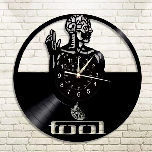 Skeletal Brain Wall Clock 9 A round Skeletal Brain Wall Clock with a vinyl record design, featuring an artistic figure and the word "tool" engraved on it, mounted on a white brick wall.