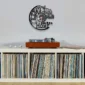 Wall decor with a kitchen-themed clock above a record player on a vinyl-filled shelf.