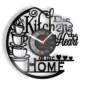 Wall clock with a black cut-out design featuring stacked cups and the phrase "The Kitchen is the Heart of the Home.