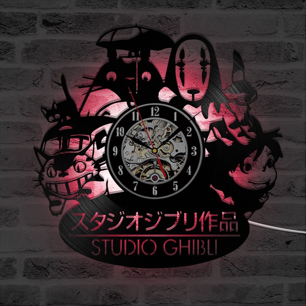 Wall clock featuring Studio Ghibli characters and logo, with gears visible behind clock hands, mounted on a brick wall.