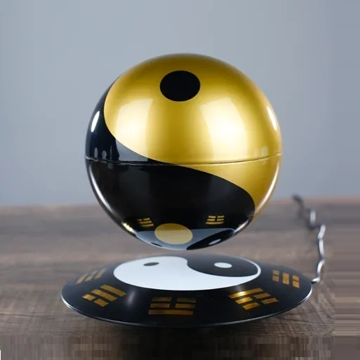 A levitating Magic Ball in black and gold, similar to the Luis de Matos floating ball, elegantly hovers over its matching base on a wooden surface.