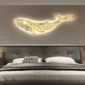 A sleek, modern bedroom features a glowing whale-shaped wall light above a neatly made bed with a gray headboard.
