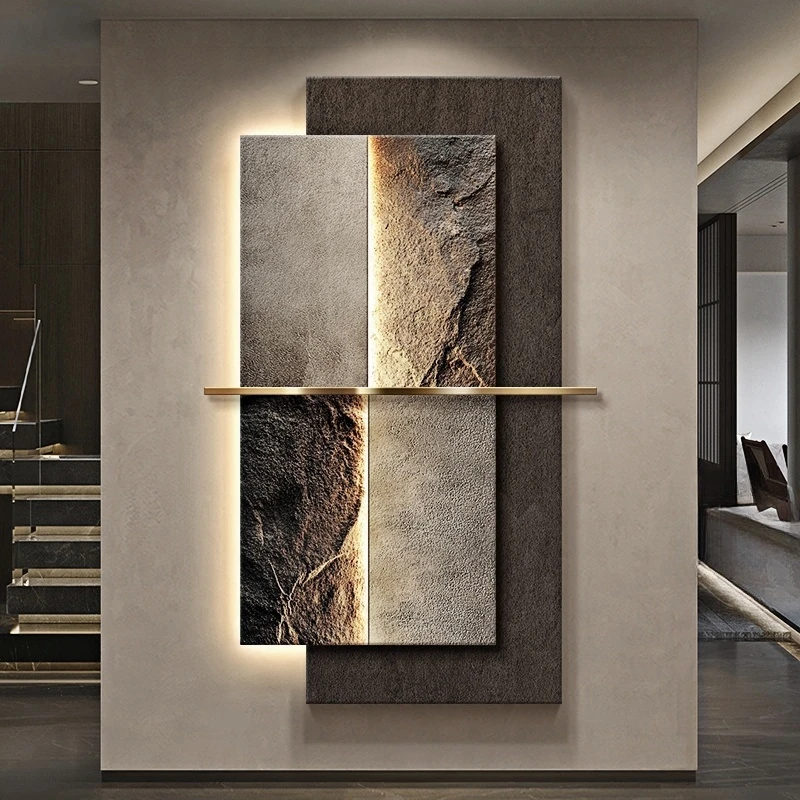 Abstract wall art with textured panels, featuring earth tones and a vertical golden bar dividing the sections. The artwork is illuminated from behind, mounted on a plain wall.